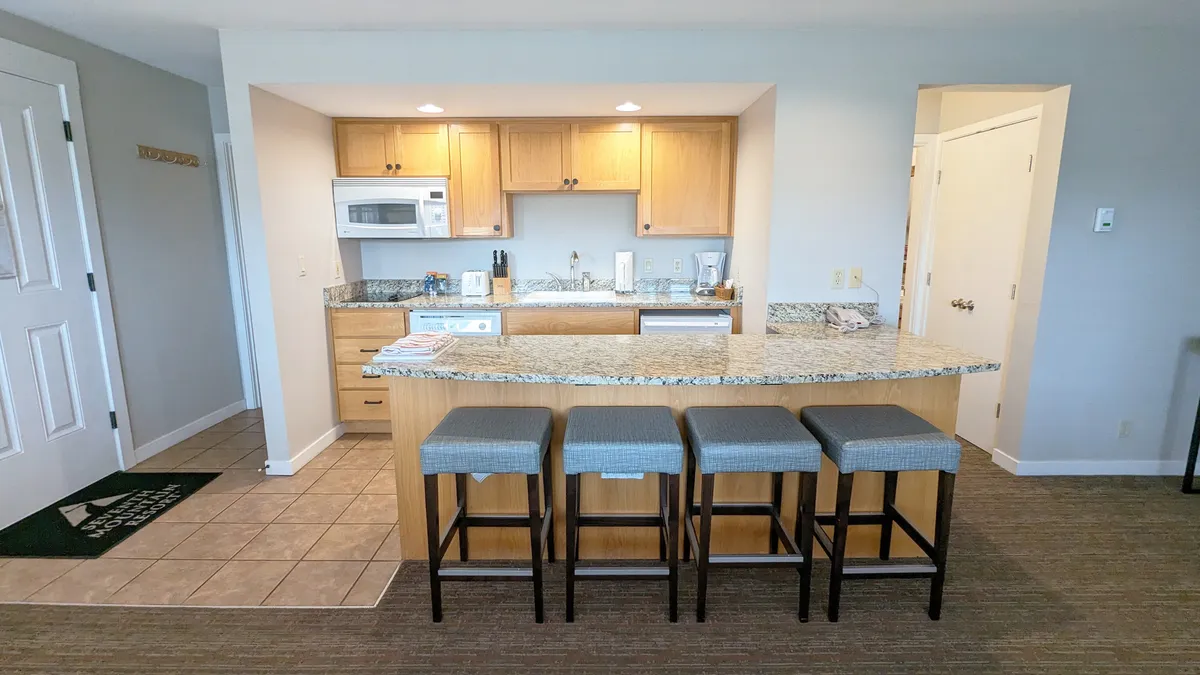 A closer look at the kitchen island set with bar stools, countertop appliances, and a warm mood perfect for cooking or enjoying an intimate meal. The scene invites thoughts of preparing breakfast before hitting the trails or sharing a celebratory brunch with loved ones.