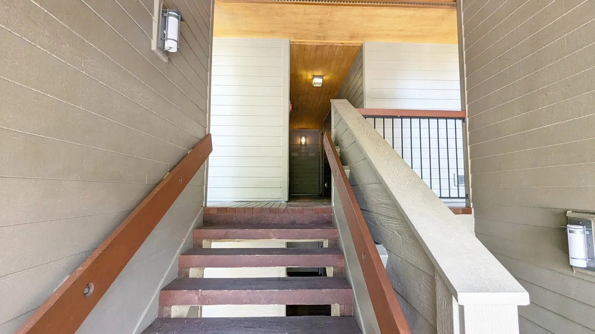 This image captures the entrance area of the property, featuring a staircase, doorway, and warm lighting. It creates a welcoming atmosphere and subtly introduces the idea of entering a peaceful retreat on the top floor.