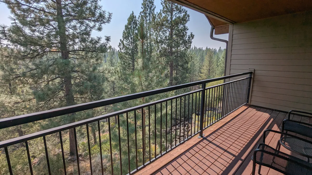 This image focuses on a peaceful balcony view, with a railing, surrounding trees, and deck flooring, highlighting the natural beauty and tranquil setting available to guests.