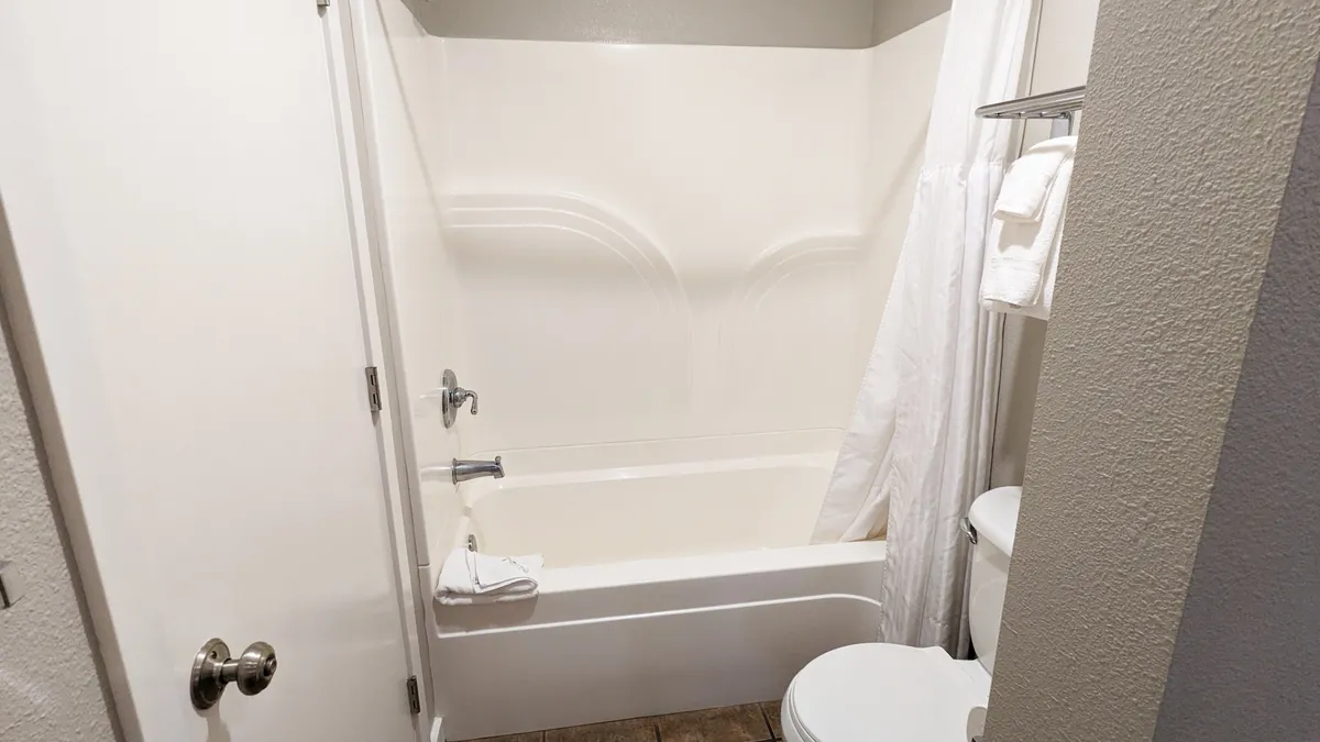 A calming bathroom setup with a spacious bathtub, toilet, and neatly arranged towels. The design emphasizes clean lines and soft textures, inviting quiet moments of self-care and relaxation after a day of adventure.